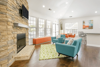 A living room with a stone fireplace and a flat screen TV mounted above it.